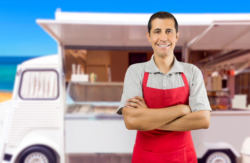 A person smiling standing outside of an ice cream truck in Norman.